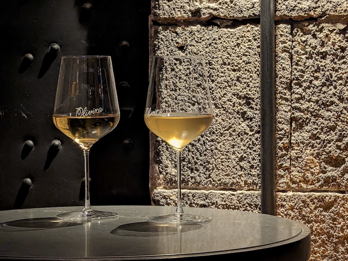 two wine glasses with 'Olivine' logo on top of black round table