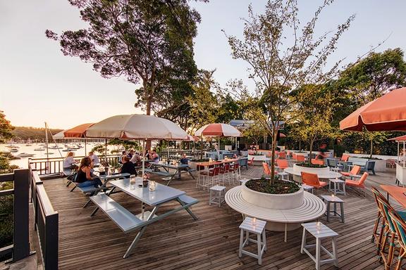 outdoor terrace overlooking water with tables and umbrellas