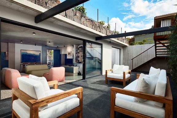 Wooden cushioned chairs at the open-air lounge of Underground House