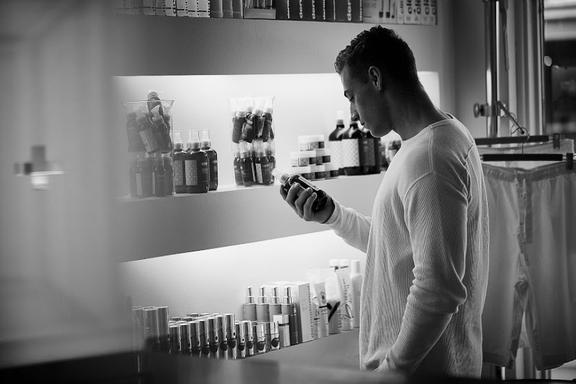 A man looking at a bottle in his hand at a shop