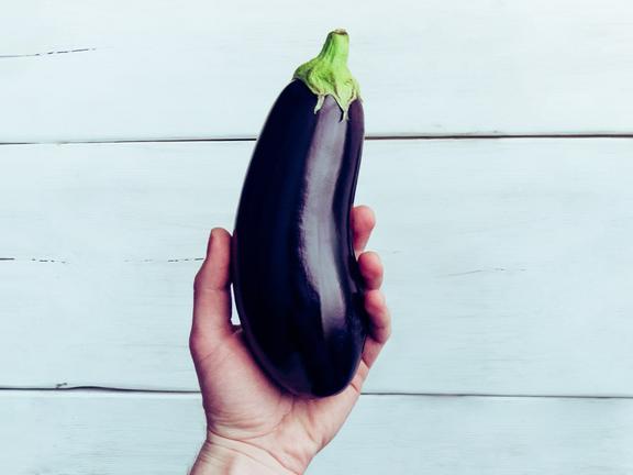 Close up of a hand holding an eggplant